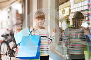 Sad little girl pointing to shop window