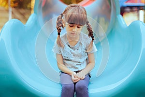 Sad Little Girl Sitting Alone in a Playground Slide