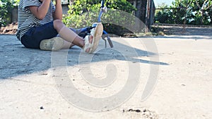 Sad little girl sitting on the ground after falling off her bike at summer park. Child was injured while riding a bicycle.