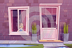 Sad little girl sitting at house window at rain