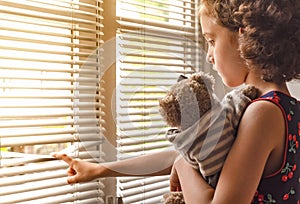 Sad little girl watching outside the house