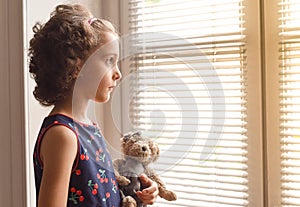 Sad little girl watching outside the house