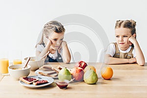 sad little sisters do not want to eat healthy breakfast photo