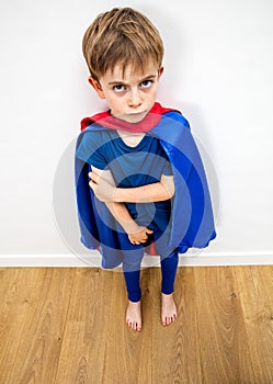 Sad little superhero boy feeling denigrated by parenthood and education photo