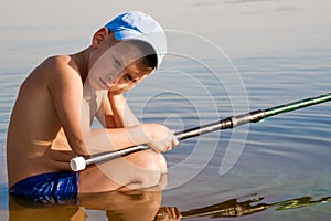 Sad and lonely kid boy sitting in the water