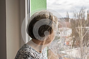 Sad lonely old woman look next to  window allone depressed abandoned