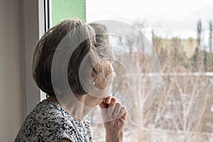Sad lonely old woman look next to  window allone depressed abandoned photo