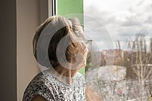 Sad lonely old woman look next to  window allone depressed abandoned