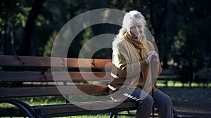 Sad lonely old woman sitting on bench in park, abandoned elderly people alone