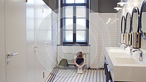 Sad and lonely teen girl sit on restroom floor alone