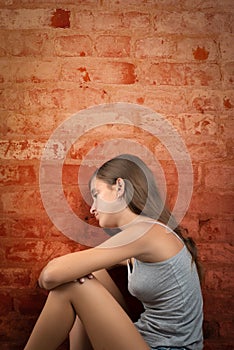 Sad and lonely teenage girl sitting on the floor