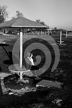 Sad, lonely, unhappy, disappointed child sitting alone on the steel Playground element. disobedience. Boy holding his