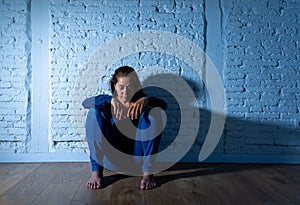 Sad lonely woman suffering from depression sitting alone and hopeless on floor at home