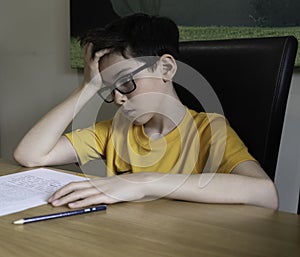 Sad looking boy doing homework during quarantine time