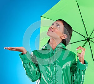 Sad, looking and a woman with an umbrella for the rain isolated on a blue background in a studio. Confused, insurance