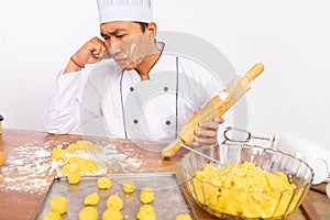 sad male chef failing to bake cake with rolling pin