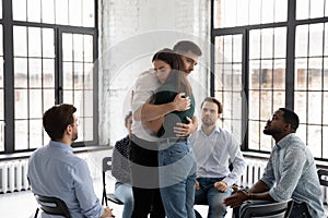 Sad male and female hugging one another on group therapy
