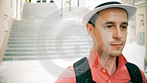 Sad male traveller wearing hat walks downstairs on the street