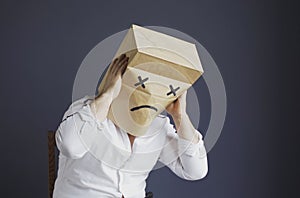 Sad man with a bag on his head, with a drawn crying emoticon