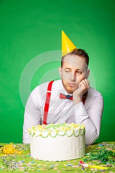 Sad man with birthday cake in studio