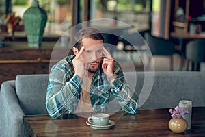 Sad man with cup of coffee in cafe