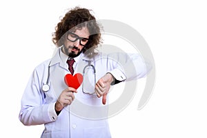 Sad man doctor holding red heart while giving thumb down