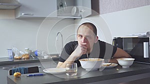 Sad man eating pasta at the table. Home in his kitchen. He worries because of his problems.