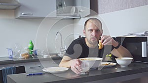 Sad man eating pasta at the table. Home in his kitchen. He worries because of his problems.