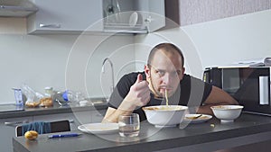 Sad man eating pasta at the table. Home in his kitchen. He worries because of his problems.