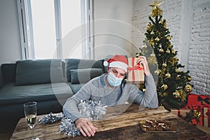 Sad man with face mask home alone at christmas missing family and friends