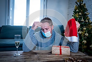 Sad man with face mask home alone at christmas missing family and friends