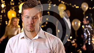 Sad man feeling lonely at party, dancing people on background, relations problem