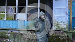 Sad man with a gas mask sits amid the ruined house