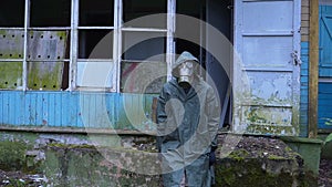 Sad man with a gas mask sits amid the ruined house