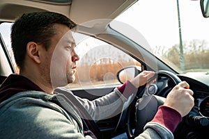 Sad man in grey sweater behind wheel of car. reeds