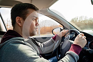 Sad man in grey sweater behind wheel of car reeds