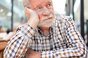 Sad man - handsome bearded elderly man sitting thoughtfully holding his head with hand, concept of unhappiness, stress depression