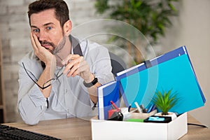 sad man with work possessions in box photo