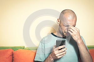 Sad man holding his cell phone in his hands and cry because his girlfriend break up with him over the text message