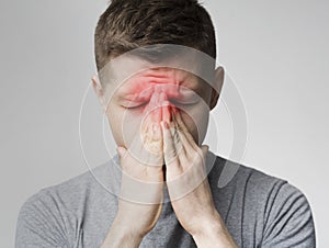 Sad man holding his nose because sinus pain