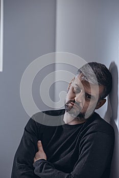 Sad man leaning against wall