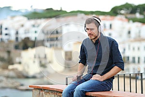 Sad man listening to music on a ledge