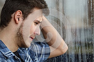 Sad man looking through window a rainy day