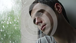 Sad man looks outside the window