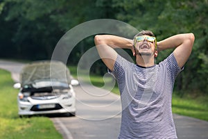 Sad man on the road next to the broken car