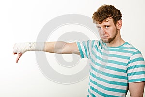 Sad man showing thumb down by bandaged hand.