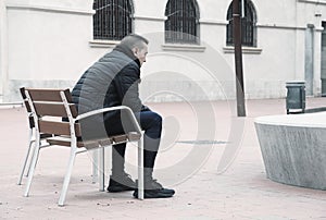 Sad man sitting in a bench in the street