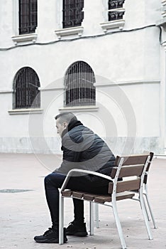 Sad man sitting in a bench in the street