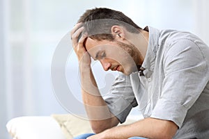 Sad man sitting on couch at home photo