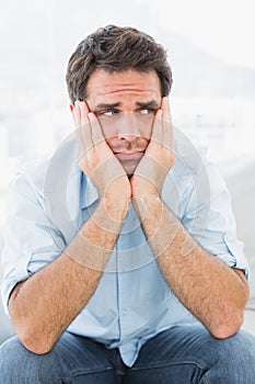 Sad man sitting on the couch looking away